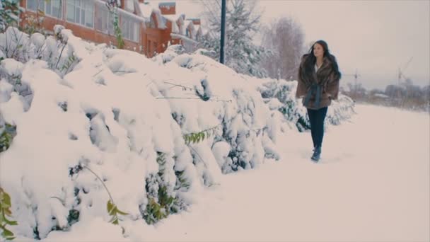 Femme brune en manteau de fourrure souriant sur le fond des bâtiments de la rue d'hiver. au ralenti — Video