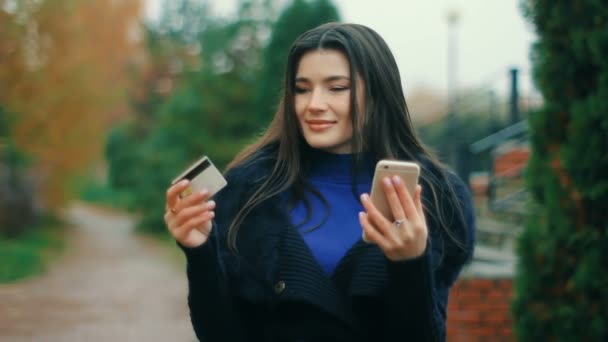Koncepcja E-commerce - brunetka kobieta trzyma karty kredytowe i smartphone zrobić zakupy — Wideo stockowe