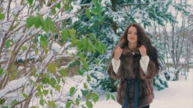 Yeşil ağaçların kış, kahverengi kürk ceket ağır çekimde yakınındaki şık esmer kız