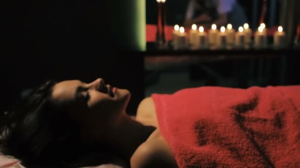 Mulher morena deitada na mesa de massagem no salão de beleza, enquanto o terapeuta profissional faz massagem nos pés — Vídeo de Stock