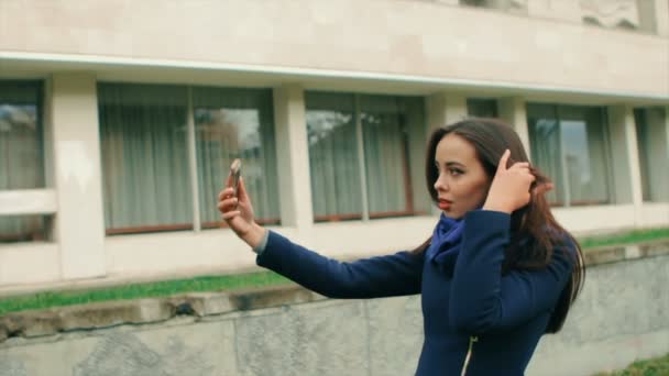 Brunette woman in blue outfit walking in city, make selfie — Stock Video