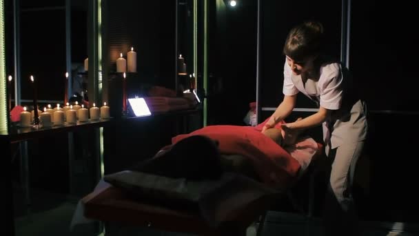 Brünette Frau liegt auf Massagetisch im Schönheitssalon, während professioneller Therapeut Magenmassage macht — Stockvideo