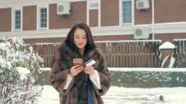 Kadın telefon ve kahverengi binaya karşı kredi kartı ile alışveriş ağır çekim yapmak