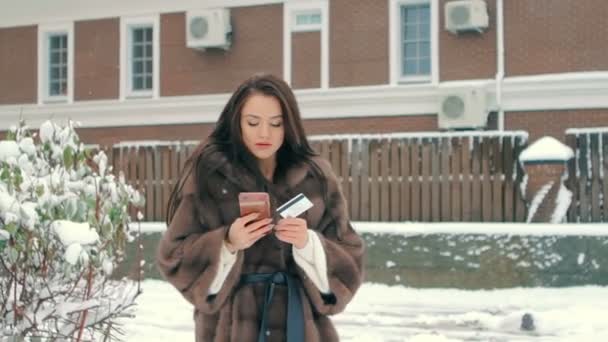 Woman with phone and credit card against brown building make shopping slow motion — Stock Video