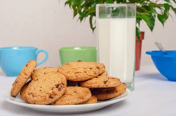 Овсяное печенье в тарелке и молоко в высоком стакане в интерьере — стоковое фото