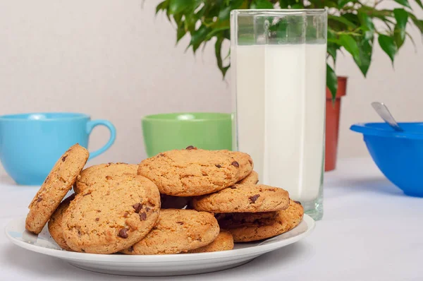 Galletas de avena en plato y leche en vaso alto en interior —  Fotos de Stock