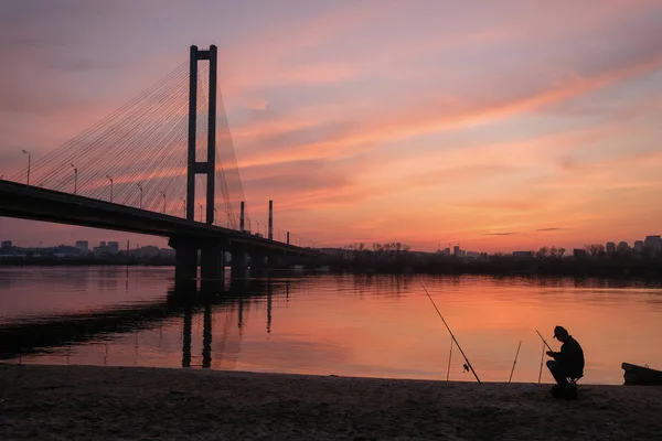 Gün batımında nehir kıyısında bir balıkçı silüeti — Stok fotoğraf