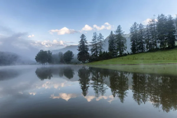 Salida del sol de verano en el lago Moutnains, nubes de colores y reflexión — Foto de Stock