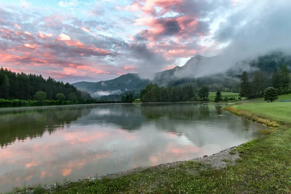 Salida del sol de verano en el lago Moutnains, nubes de colores y reflexión — Foto de Stock