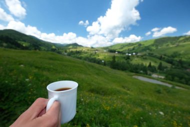 El ile beyaz bir fincan kahve Dağları nın arka planı