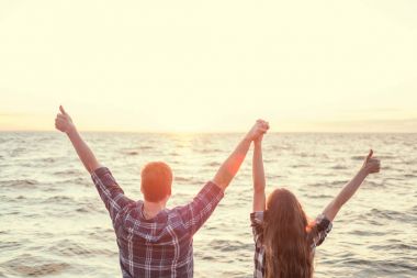 Genç çift tropik sahilde elele görünümünü arka. Silah uzanmış, kopya alanı