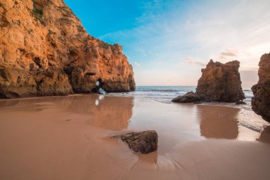 güzel Atlantik Okyanusu görünümü ufuk ile kumlu plaj, kayalar ve güneş doğarken dalgalar. Algarve, Portekiz
