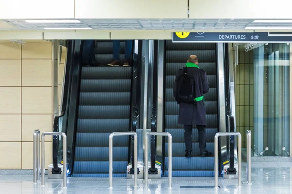 Yürüyen merdivendeki yalnız adam ya da İngilizce ve Çince 'de uluslararası havaalanında ya da arkada bavulla üst kata çıkan tren istasyonunda bulunan merdiven.