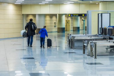 Baba ve oğul havaalanında ya da tren istasyonunda Rusça ve Çince kayıt anlamına gelen yazıyla kayıt salonuna gidiyorlar.