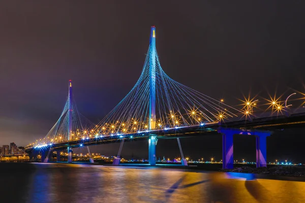 The bridge of circle highway road over Neva river near the mouth of it in the night. Night view on the buildings of Petersburg city and the Finish gulf