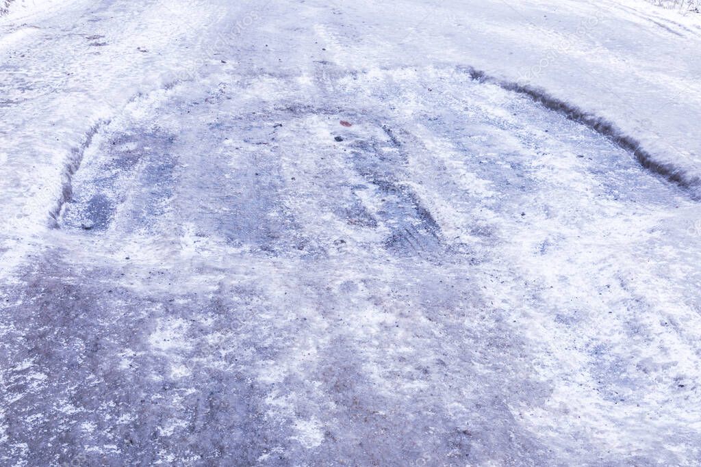 The bad asphalt winter road or way with ice, snow, puddles, pools, mud and slush