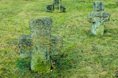 Eski Hıristiyan mezarı, mezarlıktaki yeşil çimlerin arasında yosun ve liken ile kaplanmış rünlerle haç yapar.