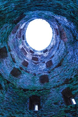 Taş ve tuğla kale veya kale kulesinde boşluklar ve çatısı olmayan bir çatı, gökyüzüne ya da tünel ışığına bakan bir kuyu gibi.