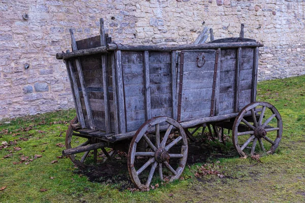在城堡或城堡石墙或砖墙后面的绿草上破碎的中世纪农村木车或马车 — 图库照片