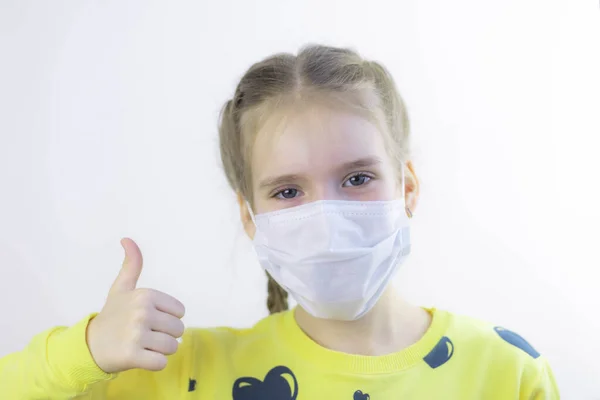 Sevinçli ve mutlu güzel neşe, sağlık hizmetindeki çocuk maskesini koruyor ya da koruyor ve beyaz arka planda kolayca çıkarılması için sarı tişört giyiyor.