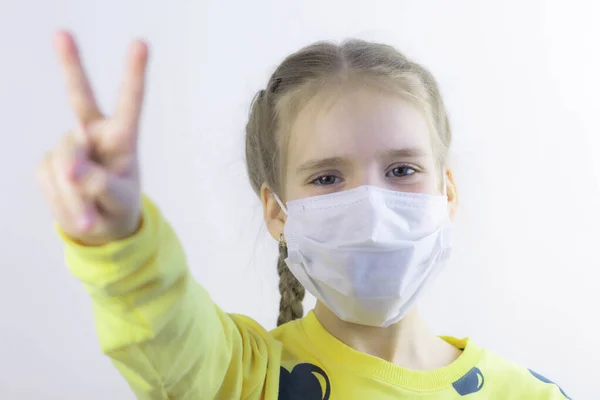 Sevinçli ve mutlu güzel neşe, sağlık hizmetindeki çocuk maskesini koruyor ya da koruyor ve beyaz arka planda kolayca çıkarılması için sarı tişört giyiyor.