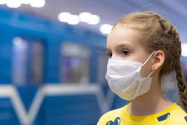 Mutlu ve mutlu bir çocuk sağlık merkezinde maskesini koruyor ya da koruyor ve sarı tişörtlü metroda ya da yeraltı koridorunda