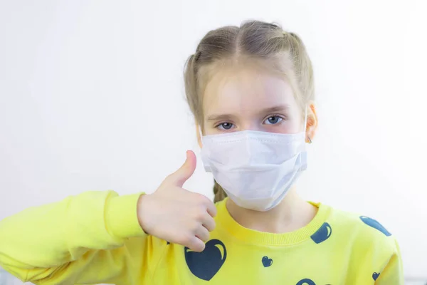 Sevinçli ve mutlu güzel neşe, sağlık hizmetindeki çocuk maskesini koruyor ya da koruyor ve beyaz arka planda kolayca çıkarılması için sarı tişört giyiyor.