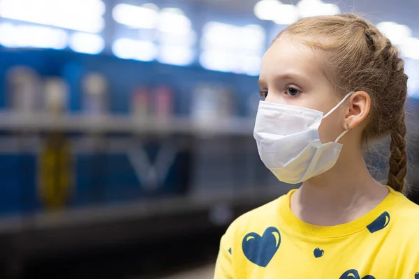 Mutlu ve mutlu bir çocuk sağlık merkezinde maskesini koruyor ya da koruyor ve sarı tişörtlü metroda ya da yeraltı koridorunda