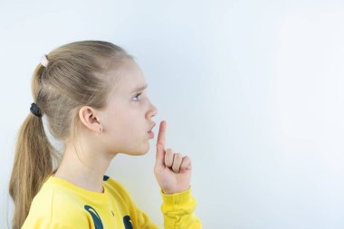 Beyaz arka planda komik, havalı, güzel ve güzel bir kız ya da tişört giyen dudaklarında işaret parmağı olan ve sessiz kalmak isteyen canlı ya da renkli bir iş.
