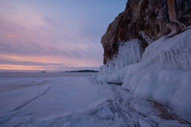 Buzlu su sıçramalarına şafak ışıklarıyla kayada kış Deniz Baykal, Kurminskiy Körfezi