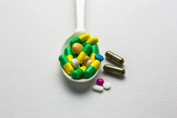 Many tablets and capsules pills on a spoon