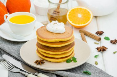 Ballı ve beyaz ahşap arka planda kremalı baharatlı balkabaklı krep yığını. Kırsal tarzda. Güzel kokulu sonbahar kahvaltısı. Cadılar Bayramı için kahvaltı..