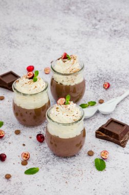 Agar agar üzerine çikolatalı krema, cam kavanozlarda krem şanti ve hafif taşlı arka plan..