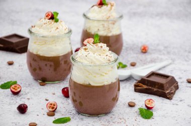 Agar agar üzerine çikolatalı krema, cam kavanozlarda krem şanti ve hafif taşlı arka plan..