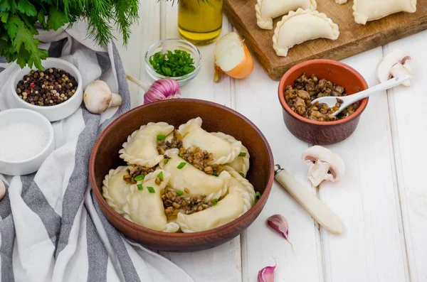 Kaynamış vegan hamur köftesi (vareniki), beyaz ahşap arka planda, patates ve soğanlı kızarmış mantar. Geleneksel Rus ve Ukrayna yemekleri. Ödünç al.