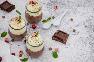 Çikolata kreması (puding, jöle, panna cotta) arpacık taşından arkaplanda cam kavanozlarda krem şanti ile agar agar üzerinde.