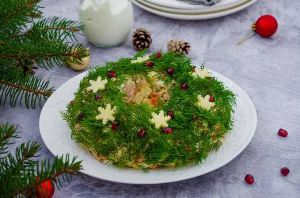 Sebzeli Olivier salatası Noel çelengi, et (sosis), yumurta ve mayonez gri arka planda. Yılbaşı ve Yeni Yıl için geleneksel Rus ve Ukrayna salatası.