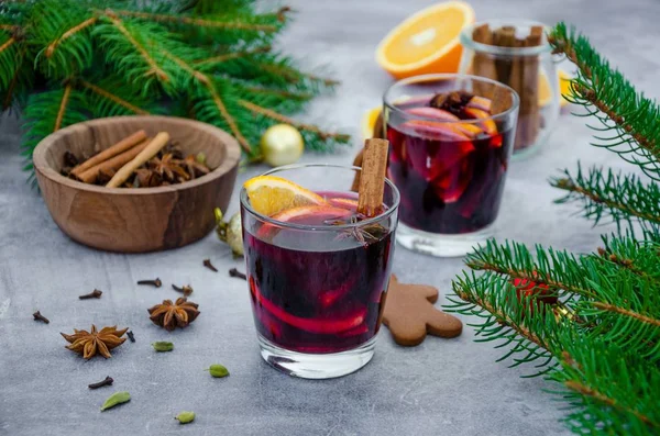 Муглированное вино в стакане с апельсином, яблоком, изюмом, корицей, звездным анисом и другими специями на сером фоне с пряниками. Запах горячего зимнего напитка. Рождественский напиток . — стоковое фото