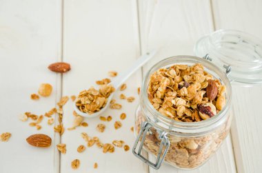 Beyaz ahşap arka planda kavanozda fındık karışımı ev yapımı tahıllı granola. Lezzetli ve sağlıklı kahvaltı..