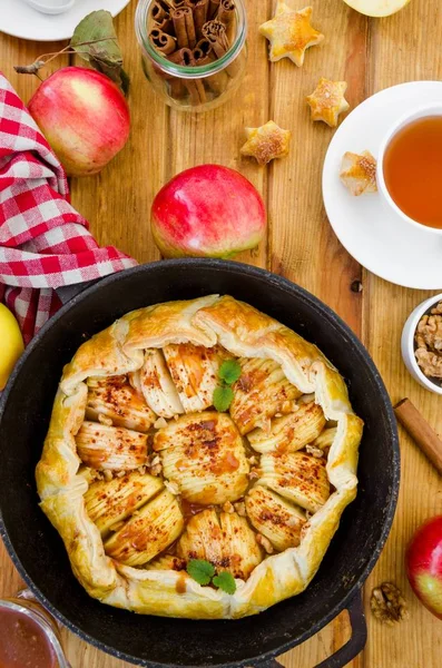 Puff pastry Apple Tart with cinnamon, walnuts and caramel in a pan on a dark wooden background. Rustic style. Vertical orientation. Top view. — Stock Photo, Image
