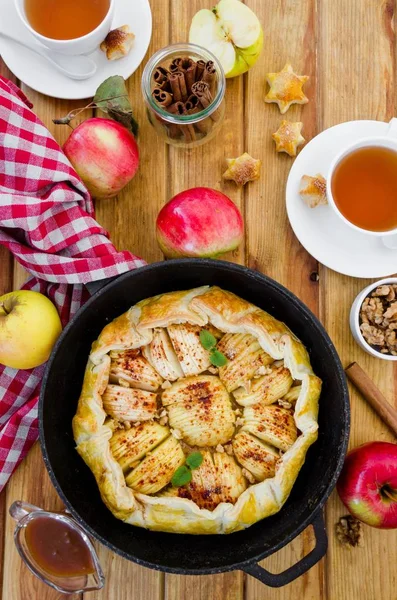 Puff pastry Apple Tart with cinnamon, walnuts and caramel in a pan on a dark wooden background. Rustic style. Vertical orientation. Top view. — Stock Photo, Image