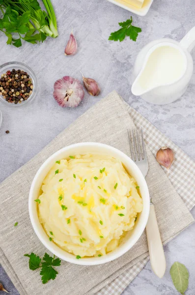 Mashed potatoes with butter, milk, garlic and green onions in a bowl on a gray background. A traditional dish of Ukrainian, Russian cuisine. Top view. Vertical orientation. — Stock Photo, Image