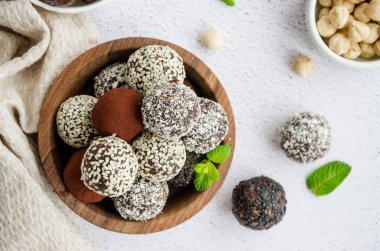 Enerji topları. Hurma mantarı, ceviz, fındık ve arka plandaki tahta kasede kakao. Sağlıklı tatlı, şekersiz, glütensiz. Yatay oryantasyon. Üst görünüm, kapat.