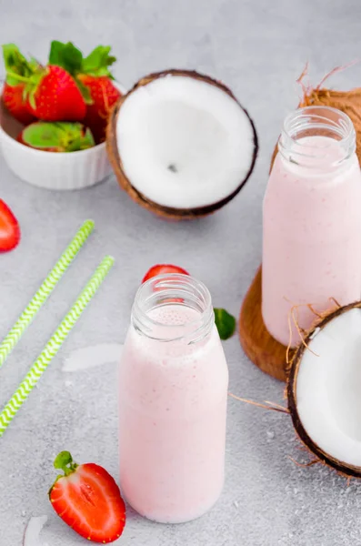 Batido de coco de fresa sobre leche de coco en un frasco de vidrio con una paja sobre un fondo gris. Concepto de comida saludable. Orientación vertical . —  Fotos de Stock