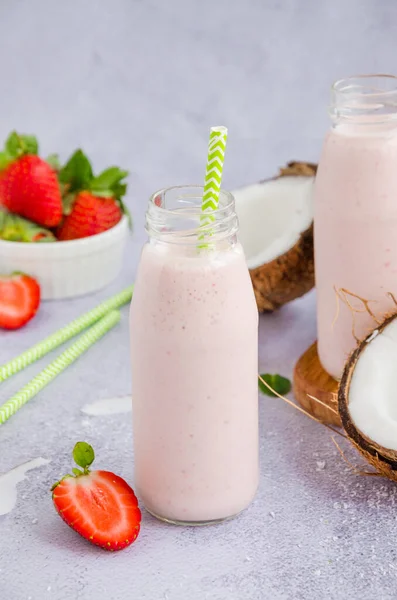 Batido de coco de fresa sobre leche de coco en un frasco de vidrio con una paja sobre un fondo gris. Concepto de comida saludable. Orientación vertical —  Fotos de Stock