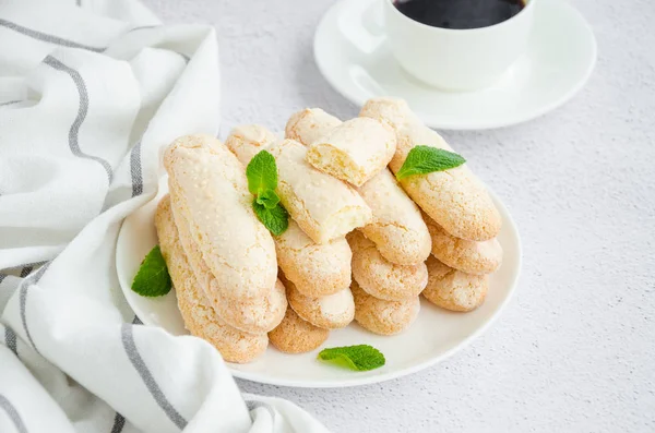 Ev yapımı İtalyan kurabiyeleri Ladyfingers (savoyardi) beyaz bir tabakta, arka planda. Tiramisu için bisküvi. Yatay oryantasyon. Kapat.