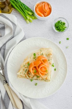 Geleneksel Rus ince krepleri ya da peynirli krepler, otlar ve açık arkaplanda tütsülenmiş somon balıkları. Tatil Maslenitsa 'sı. Dikey yönelim, üst görünüm.