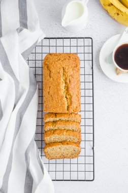 Ev yapımı lezzetli muzlu ekmek, fındıklı ve soğutma rafında tarçınlı bir fincan kahve, süt ve taze muzlu dikey oryantasyon. Üst görünüm
