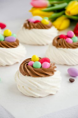 Çikolata kremalı ve renkli şekerli Mini Pavlova Kuş Yuvası. Merengue Kurabiyeleri. Çocuklar için yemek fikri. Paskalya pastası. Dikey oryantasyon. Kapat.