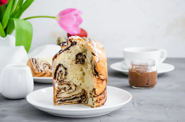 Paskalya geçmişi. Paskalya pastası - Cruffin, Kraffin veya Kulich çikolatalı fındık kreması ve şeker jöleli beton arka planda beyaz bir tabakta. Yatay oryantasyon. Boşluğu kopyala